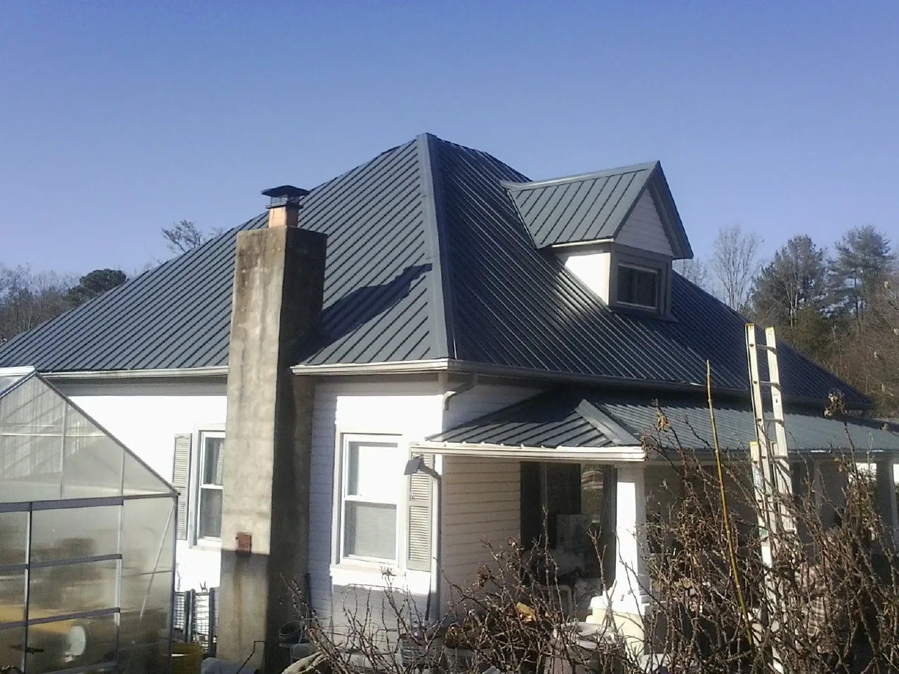Dark blue standing seam metal roof on a white farmhouse with dormer — Slate & Tile Roof Repair by Roofing Brothers in Idaho Falls