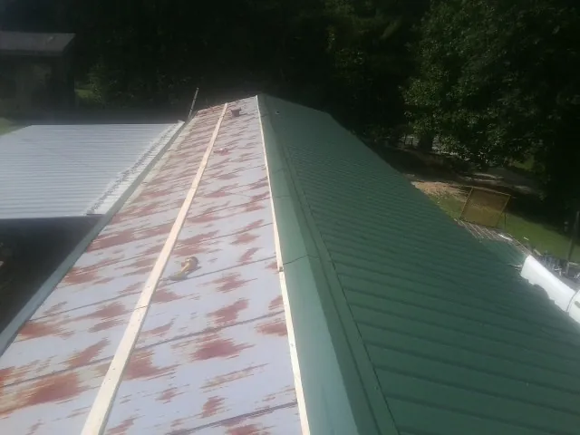 Old rusted panels beside newly installed green metal roofing — Wind Damage Roof Repair by Roofing Brothers in Idaho Falls