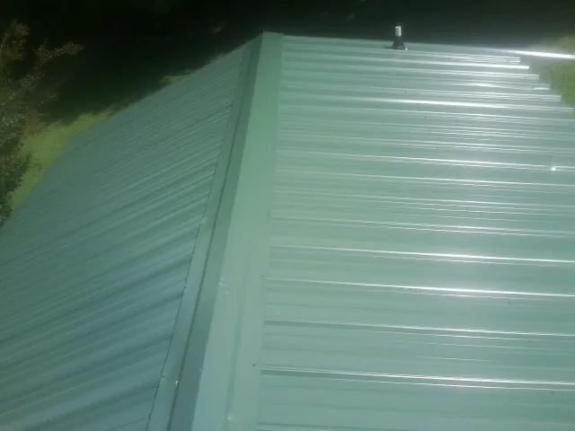 New green metal panels meeting at the ridge of a roof — Flat Roof Repair work by our crew in Idaho Falls