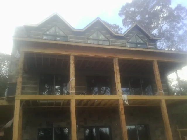 Dormers and porch framing on a large log home under construction — Roof Coating work by our crew in Idaho Falls