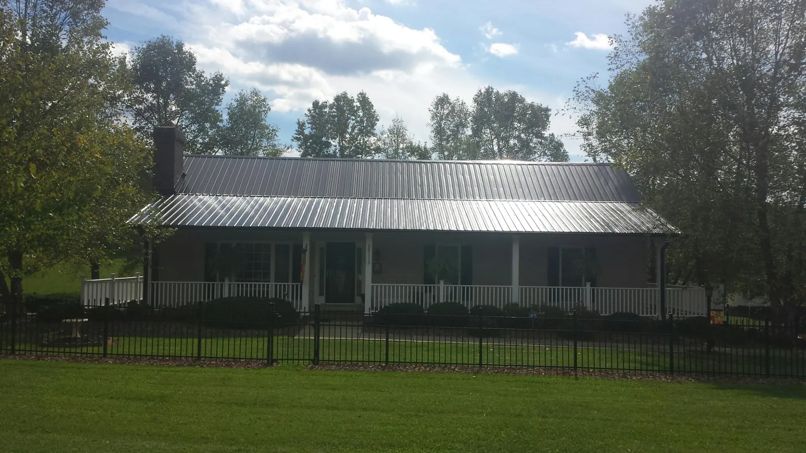 Gray metal roof on a brick ranch with a full width front porch — Gutter Guard Installation work by our crew in Idaho Falls