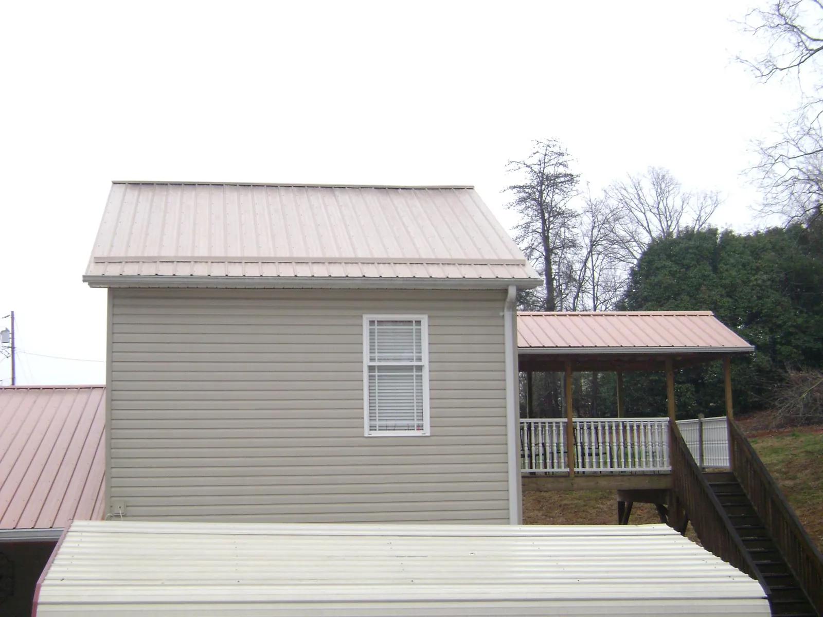 Tan metal roofs on a two story addition and attached porch, from a Roof Replacement job in Idaho Falls