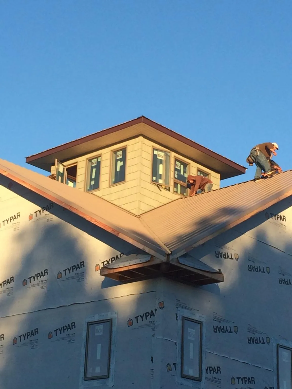 Roofers working around a rooftop cupola on a new metal roof at sunset — Roof Waterproofing in Idaho Falls by Roofing Brothers